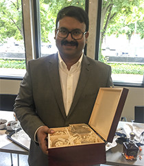 Arghya Bhowmik at his PhD defence, holding a gift from his colleagues: An engraved whiskey bottle with his name